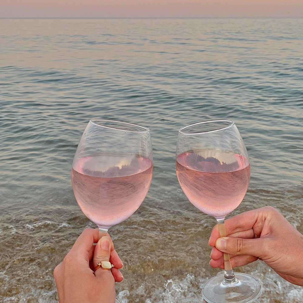 Two glasses of rosé raised over the sea