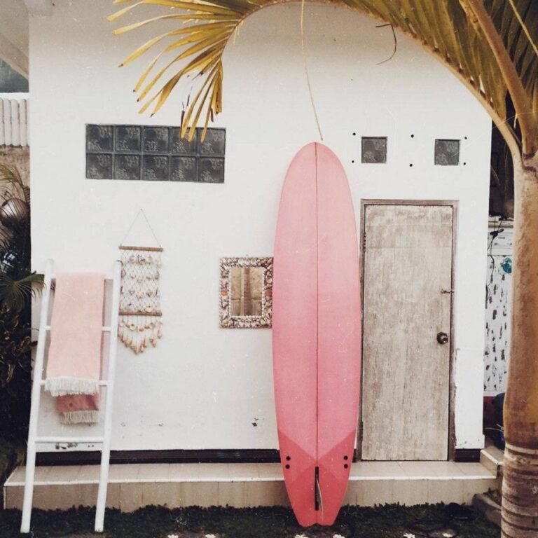 Pink surfboard outside a white beach house