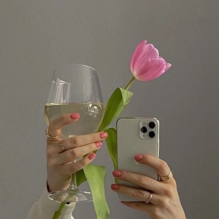 Hand holding a phone and a single pink tulip
