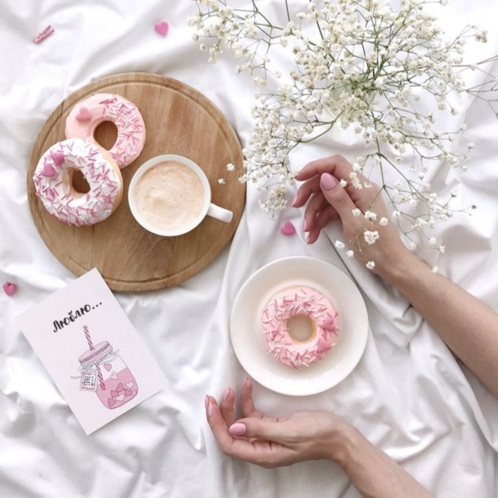 Pink tea and a sprinkled donut on white linen