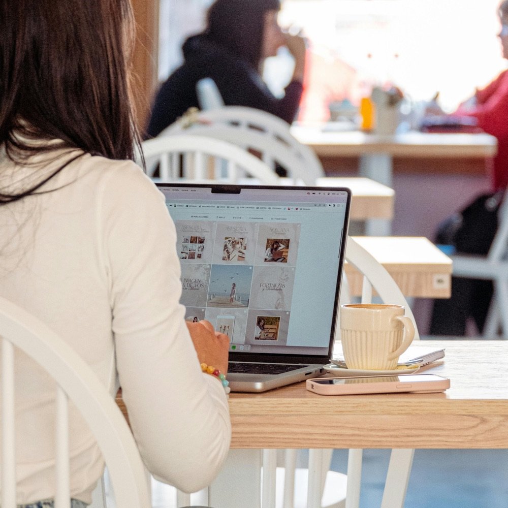 Woman working on a laptop at a bright café table