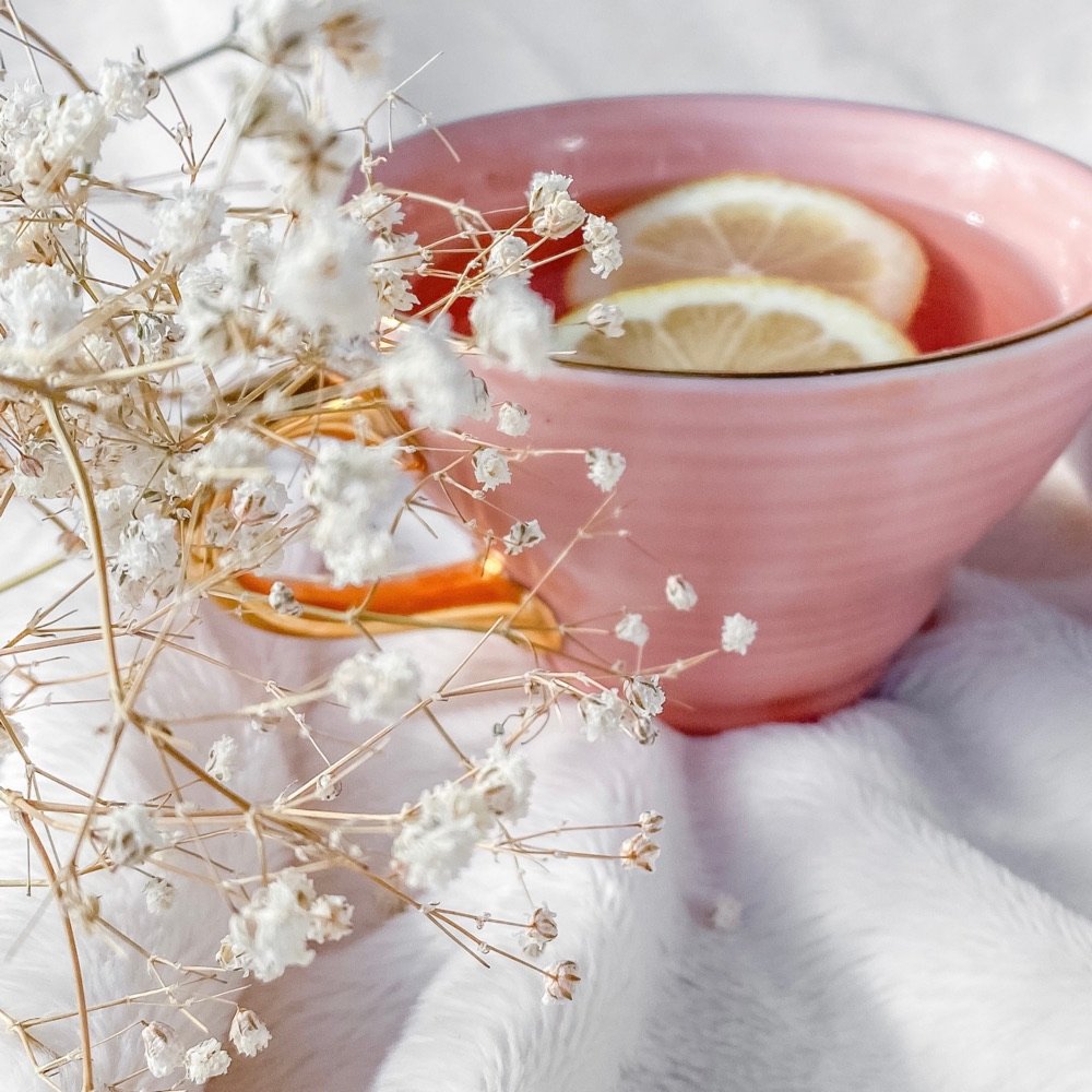 Pink bowl of tea with lemon among white flowers