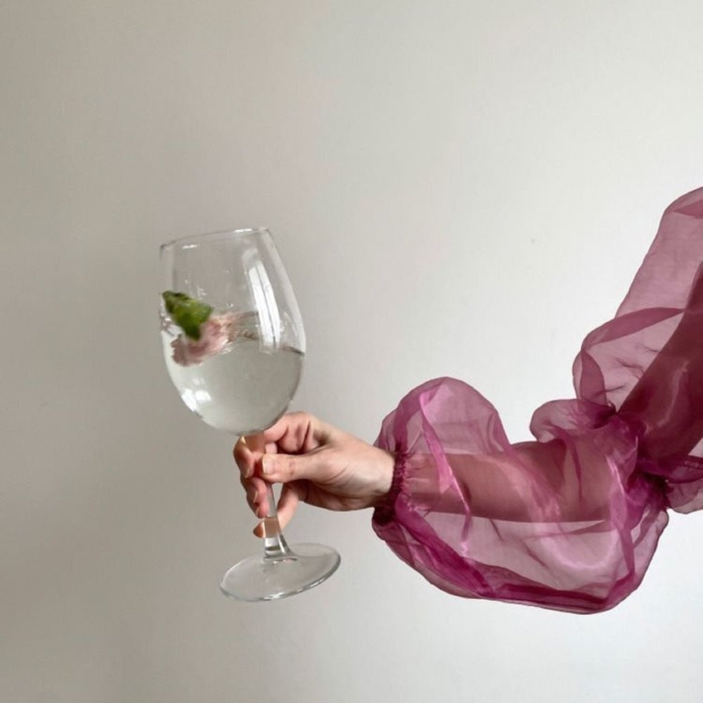 Hand holding a glass of white wine in a pink sleeve