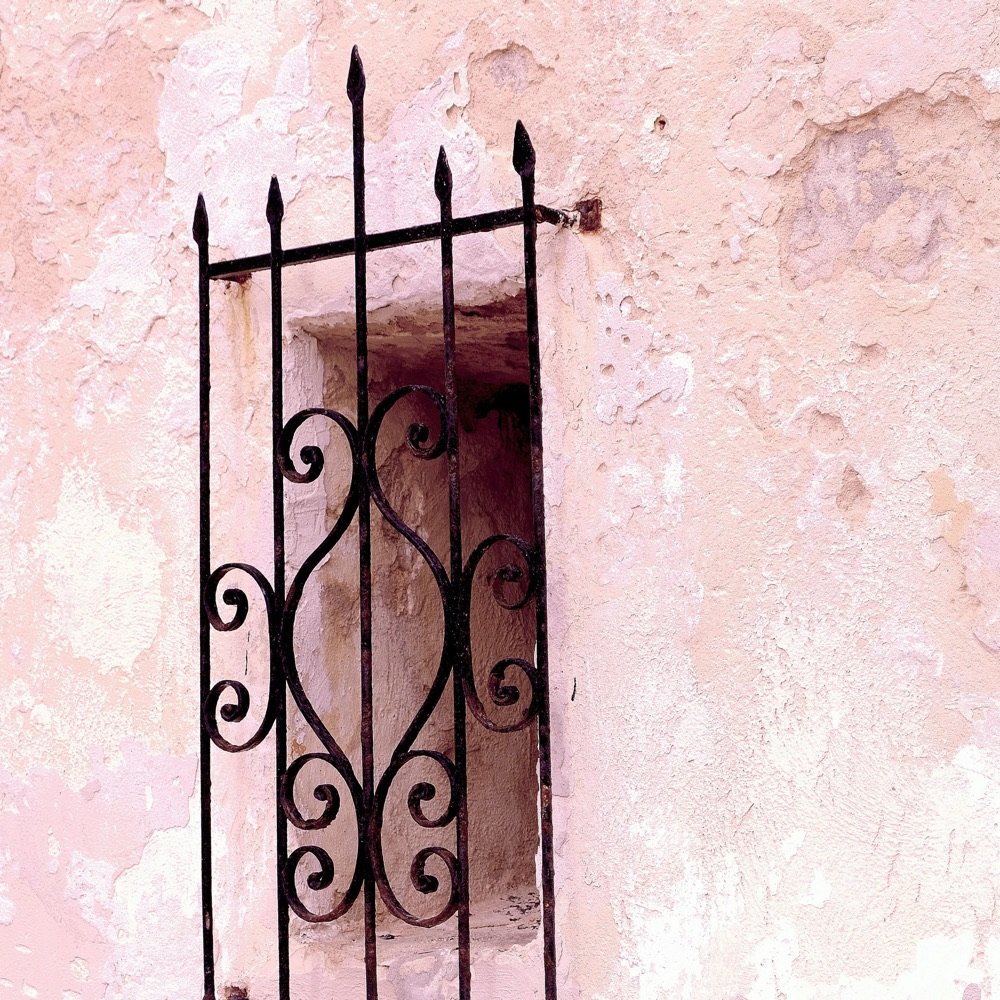 Wrought iron gate against a pink wall