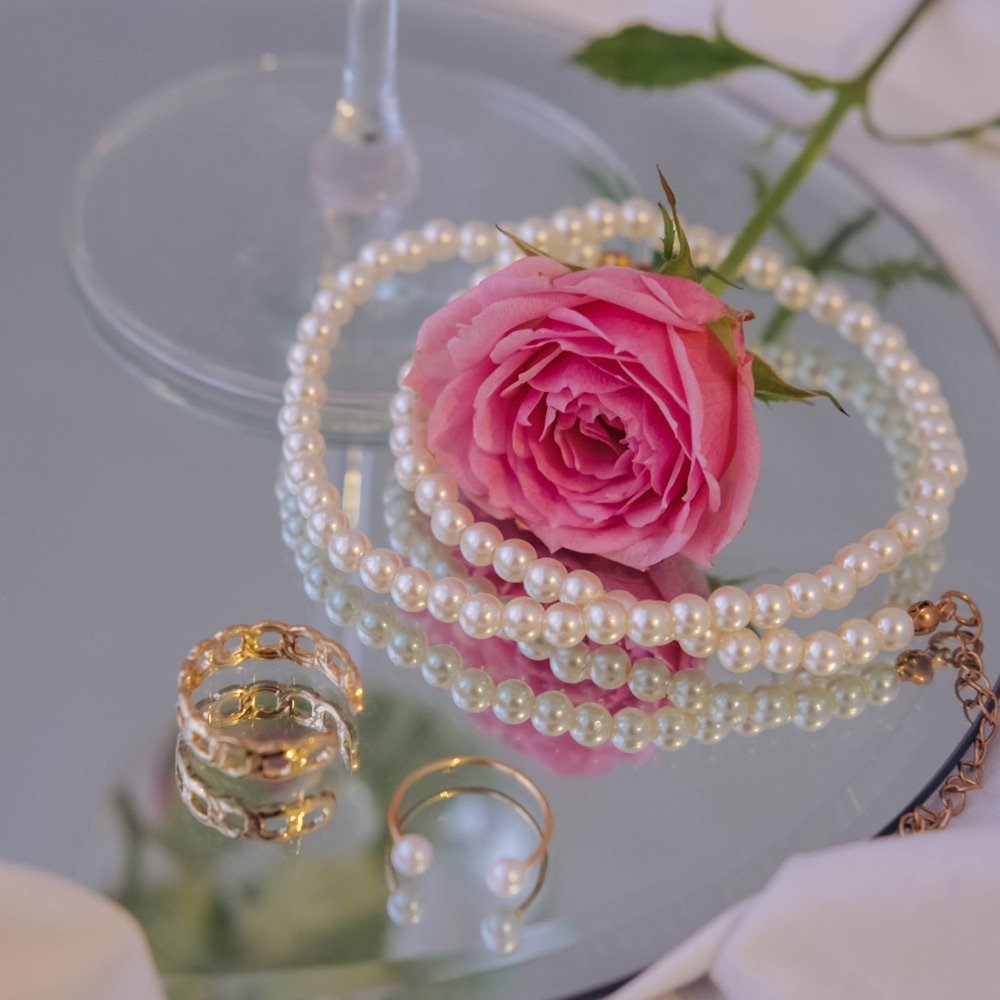 Pink rose with pearls on a glass tray