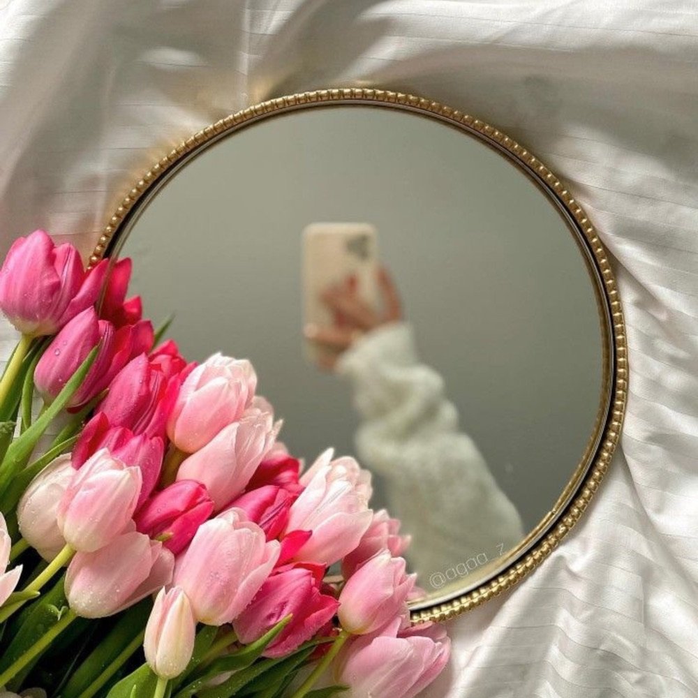 Pink tulips beside a round mirror