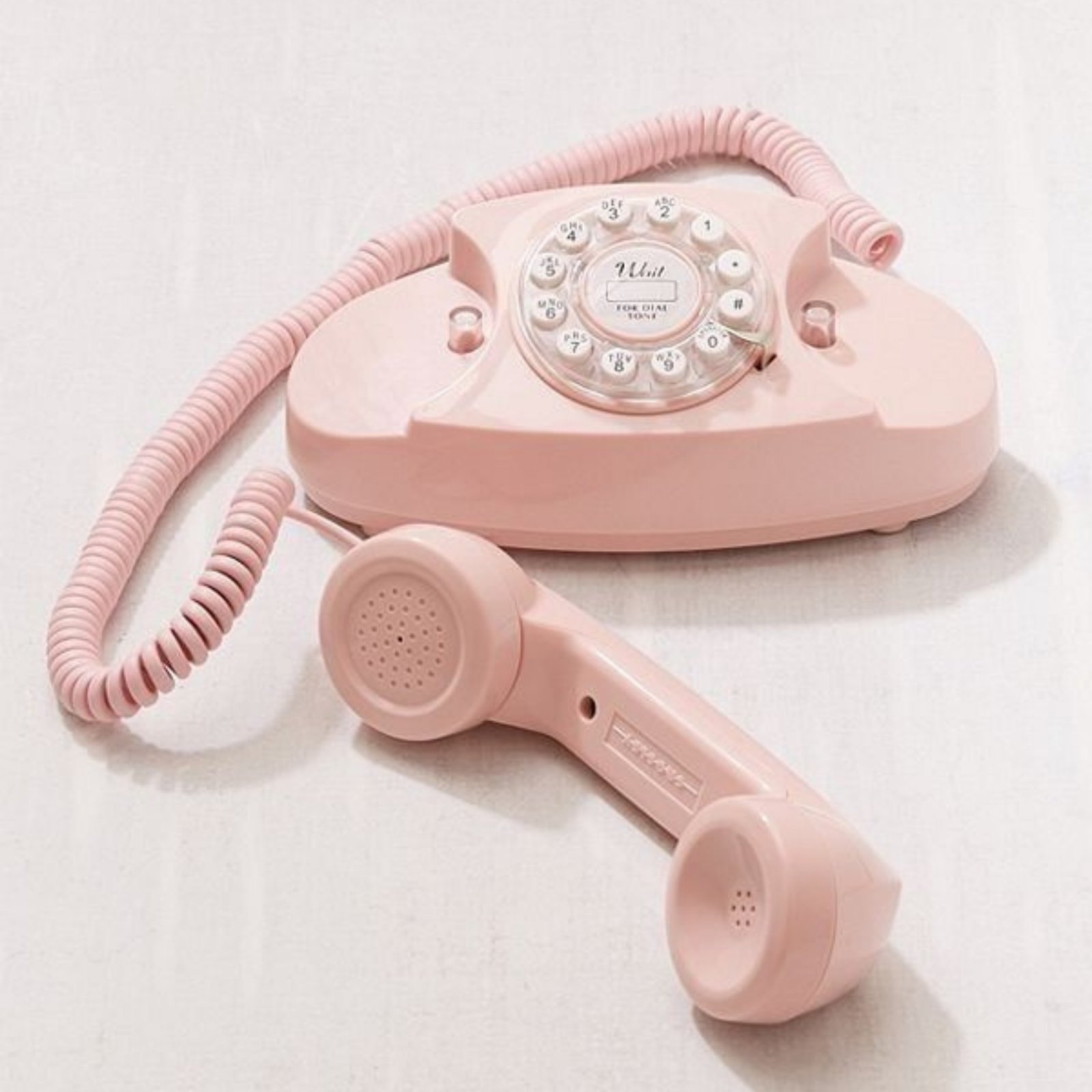 Retro pink rotary telephone on a white background